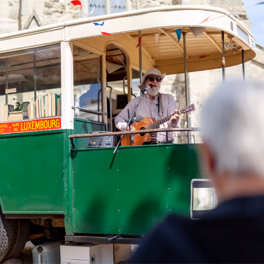 A musician playing guitar on a vintage bus