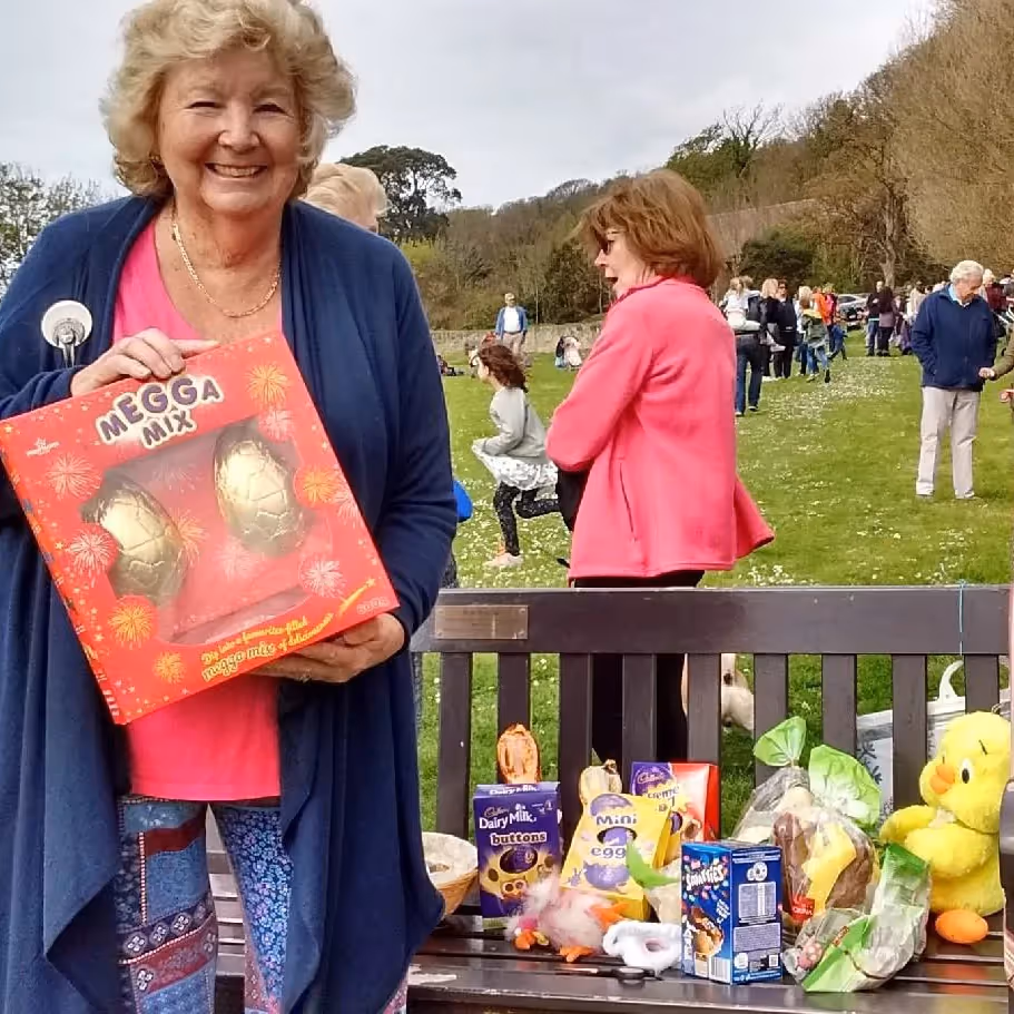 A lady with a stack of prizes for winners of a community duck race