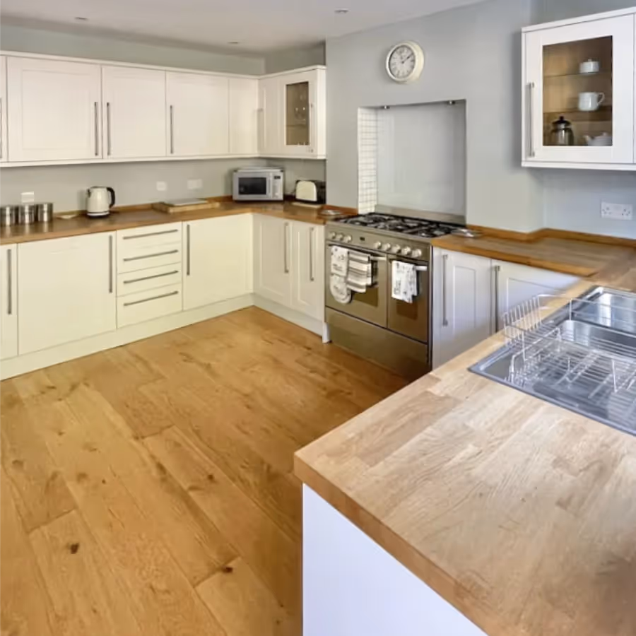 A large kitchen with cream units and a wooden floor