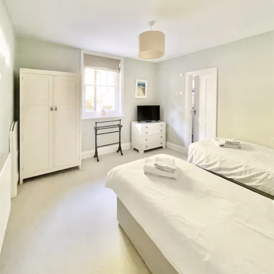 A white bedroom with twin beds and white furniture