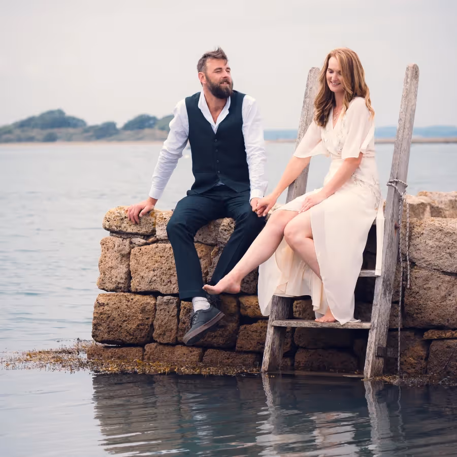A bride and groom sitting on a quayside