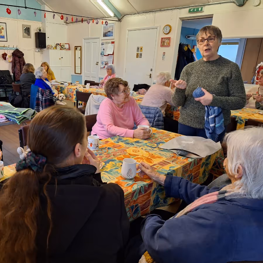 A lady giving a talk at a knitting meeting