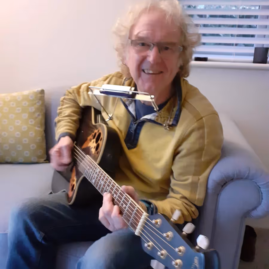 A man playing guitar and harmonica