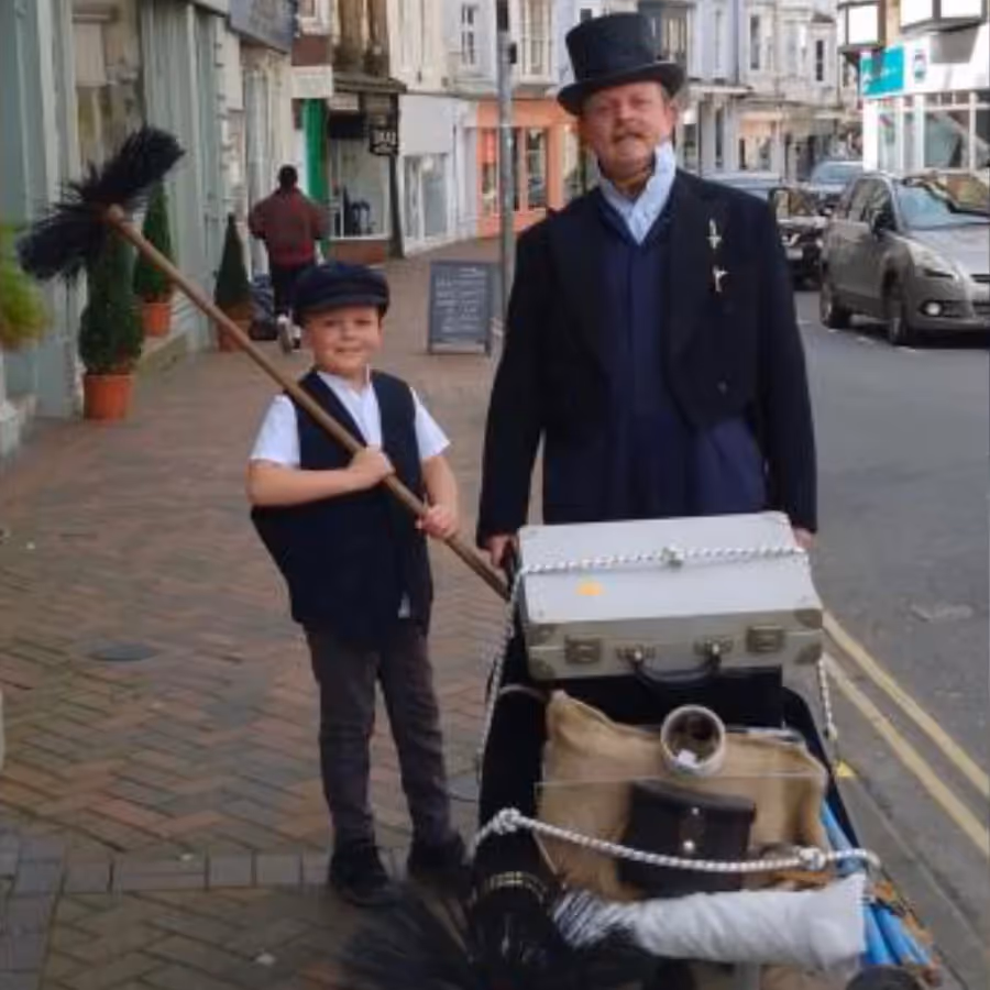 A man and a child dressed as Victorian chimney sweeps