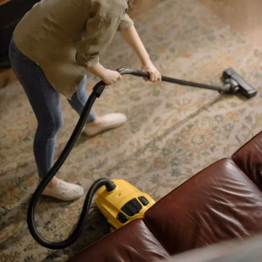 Someone vacuuming a floor rug
