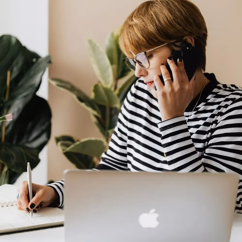 A lady writing whilst on the phone