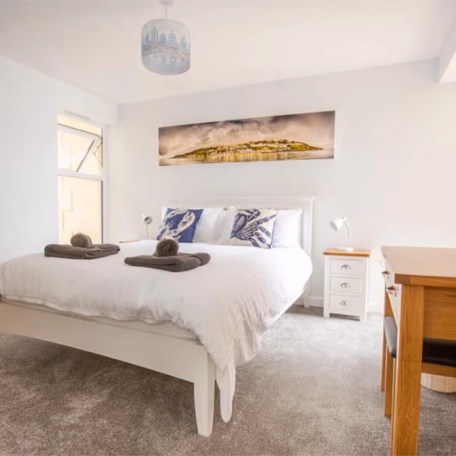 A white and blue bedroom with white and pine furniture