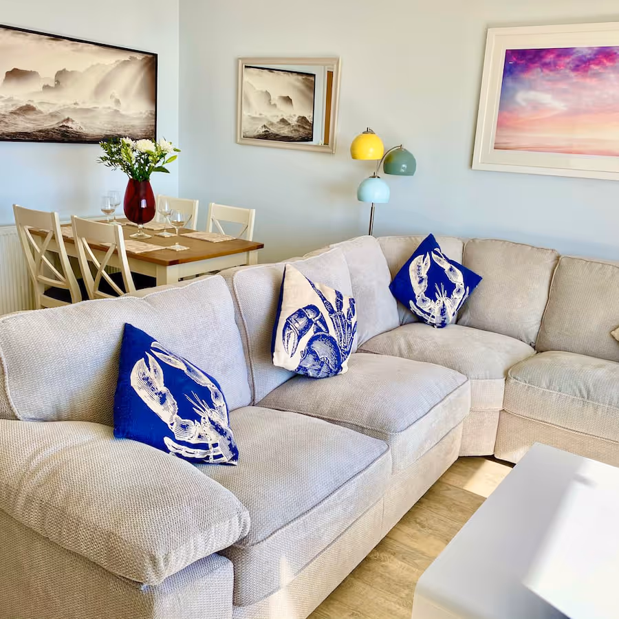 A coastal themed room with a corner sofa and dining furniture