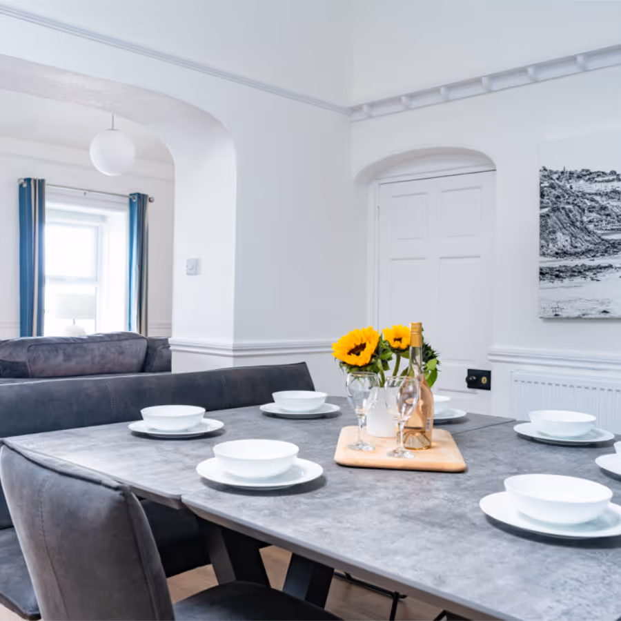 A large grey dining table in a white room