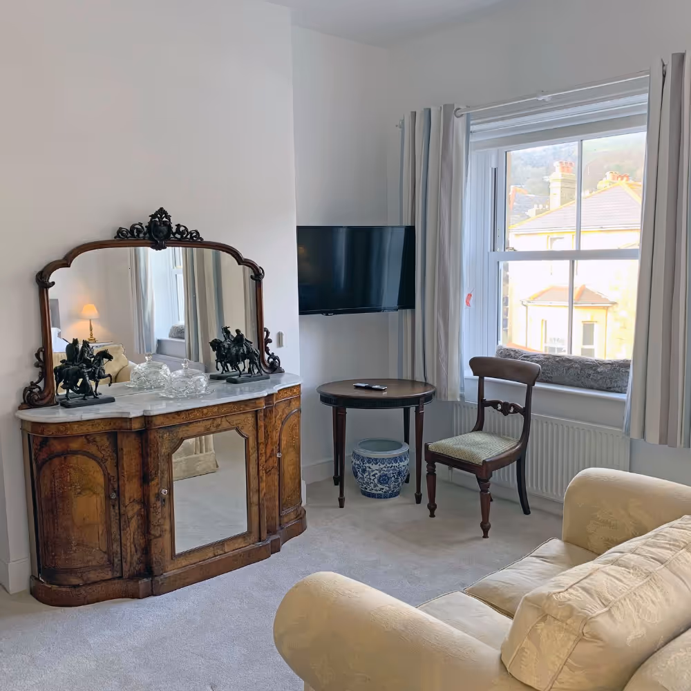 A room with an antique dresser and gold sofa