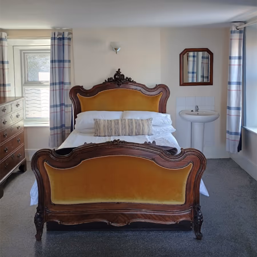 A french carved bedstead in a cosy bedroom