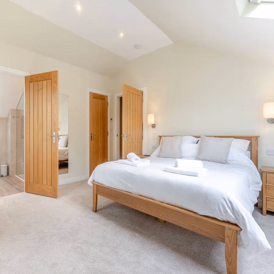 A large neutral bedroom with oak furniture