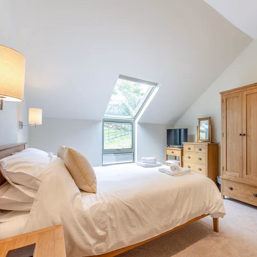 A neutral attic bedroom with oak furniture