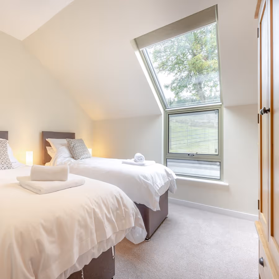 A neutral attic twin bedroom with oak furniture