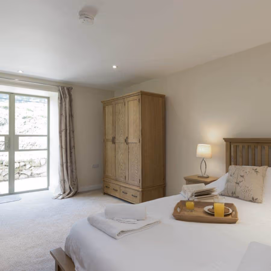 A large neutral bedroom with oak furniture