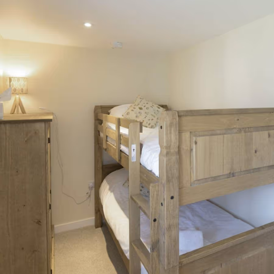 A small bedroom with oak bunk beds