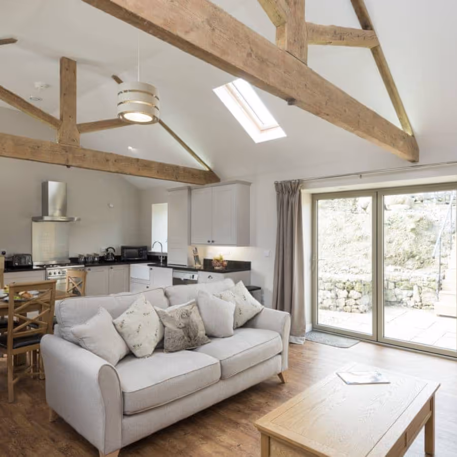 An open plan living room and kitchen with an oak beamed ceiling