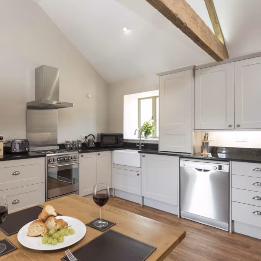 A white modern kitchen with an oak beamed ceiling