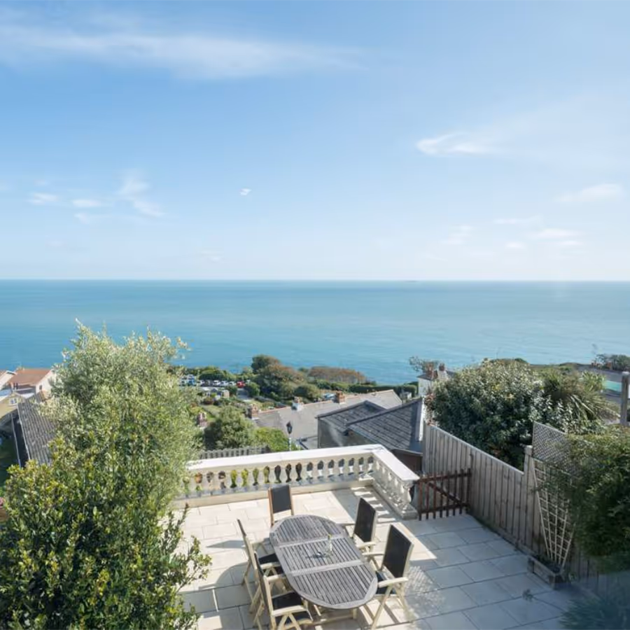 Looking down to a large outdoor terrace with a panoramic view of the sea