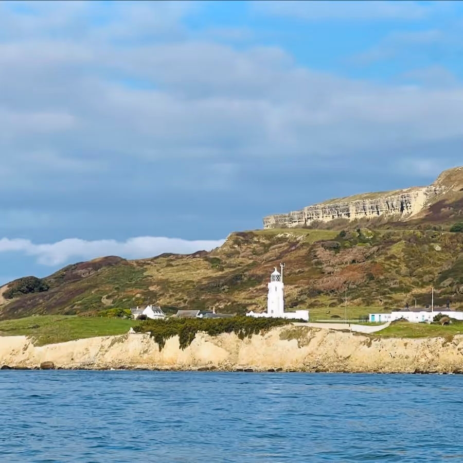 A lighthouse on the shore from a boat on the water