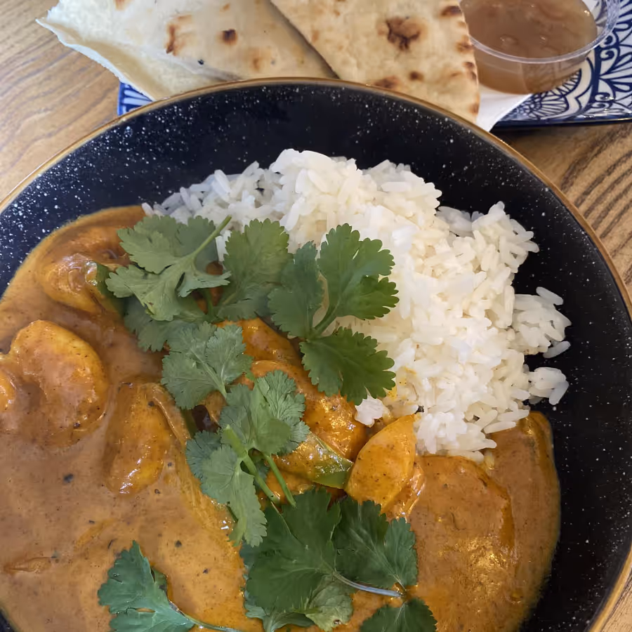 A pate of curry and rice with naan bread on the side
