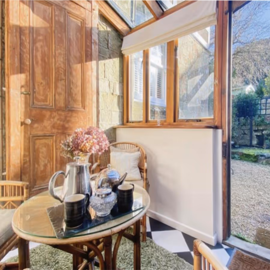 A small room with cane furniture and a door leading to a garden