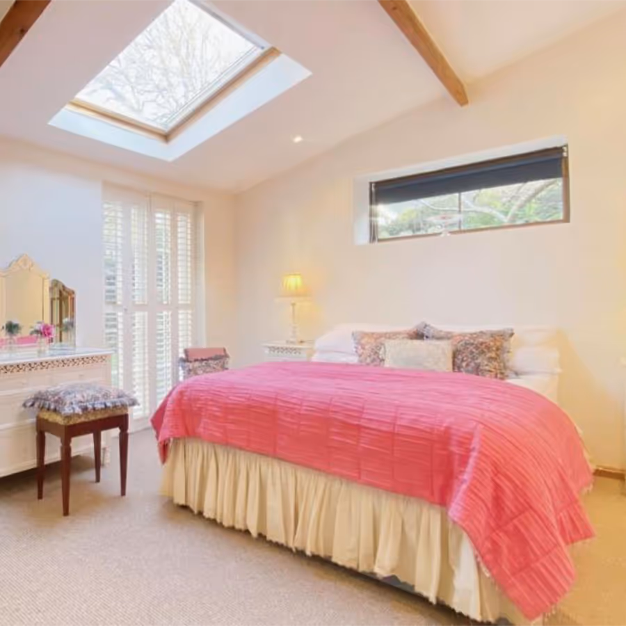 A bedroom with a lofty ceiling and roof window