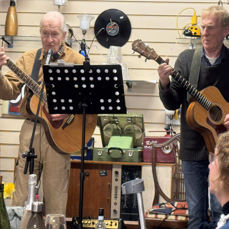 Two men singing and playing guitar in a cafe