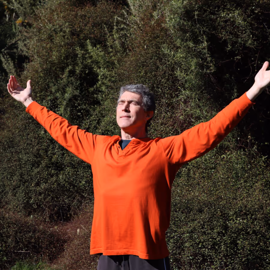 A man wearing an orange top in a yoga pose