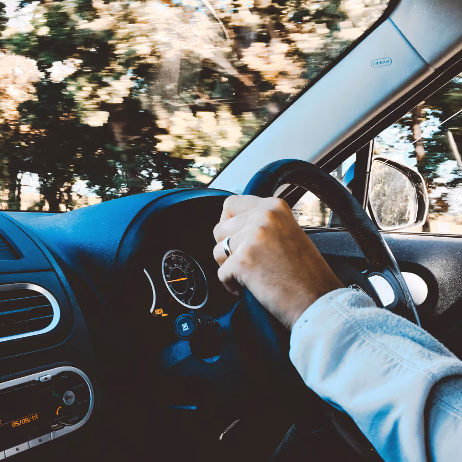 Man's hands on a car steering wheel