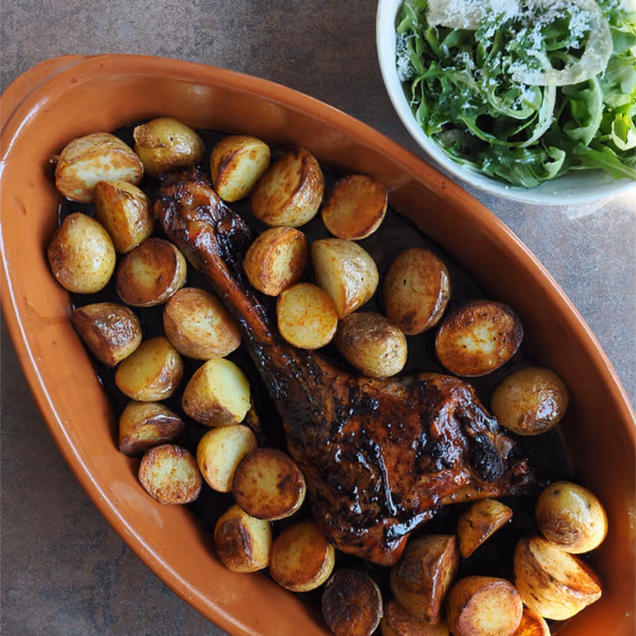 A dish of roasted baby potatoes and a bowl of greens
