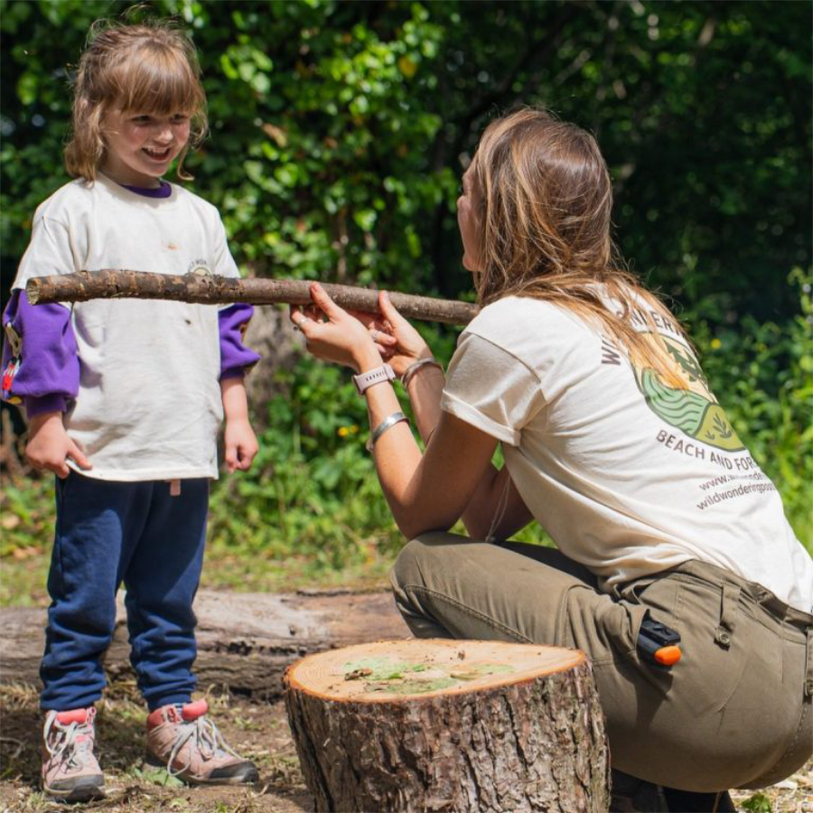 A lady teaching girl skills in a forest