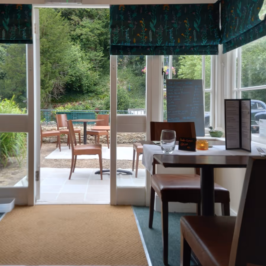 Tables inside a cafe looking towards a door and a garden beyond