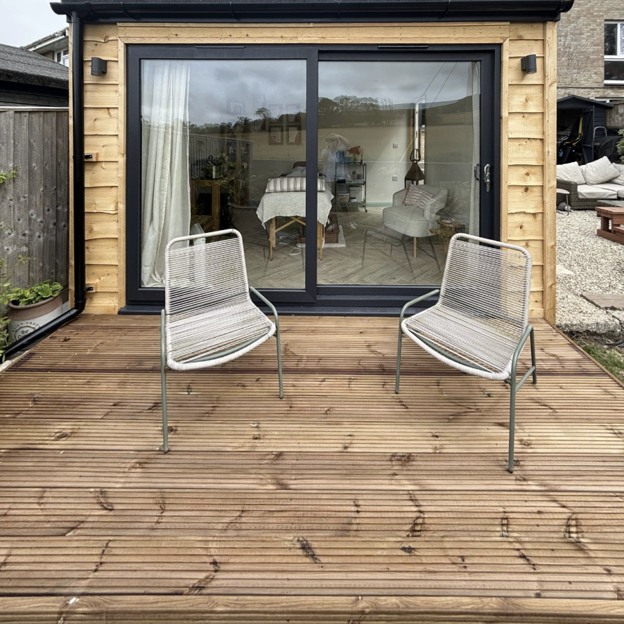 A garden cabin with a wooden deck and relaxing chairs