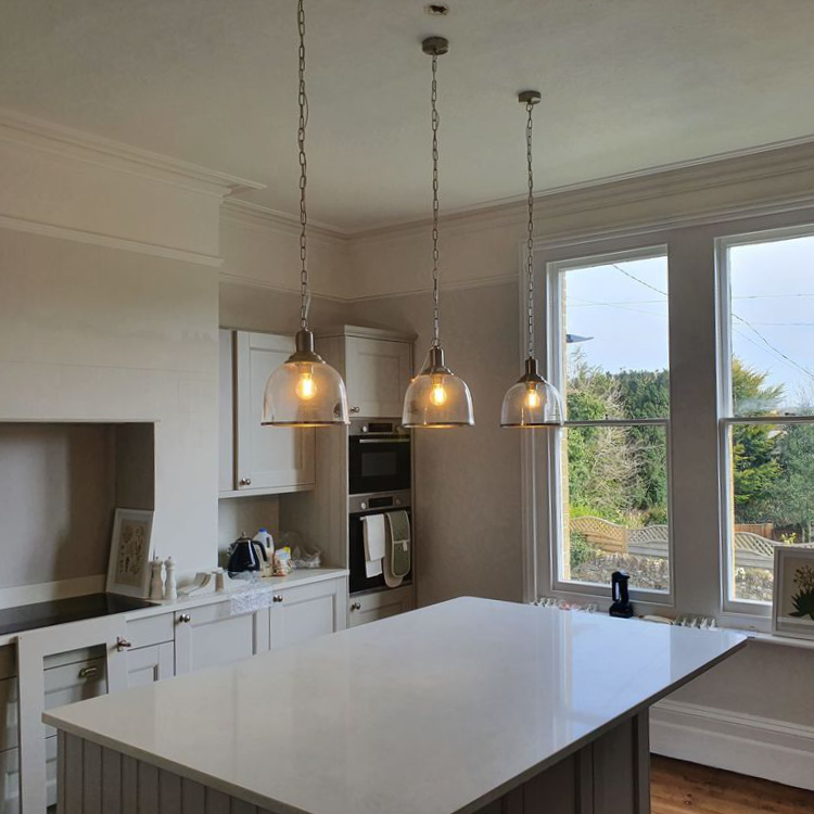 A white kitchen with modern pendant lighting.
