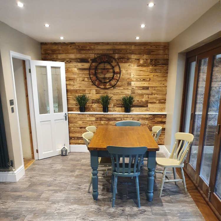 A dining room with a blue and pine table and exposed brick wall.