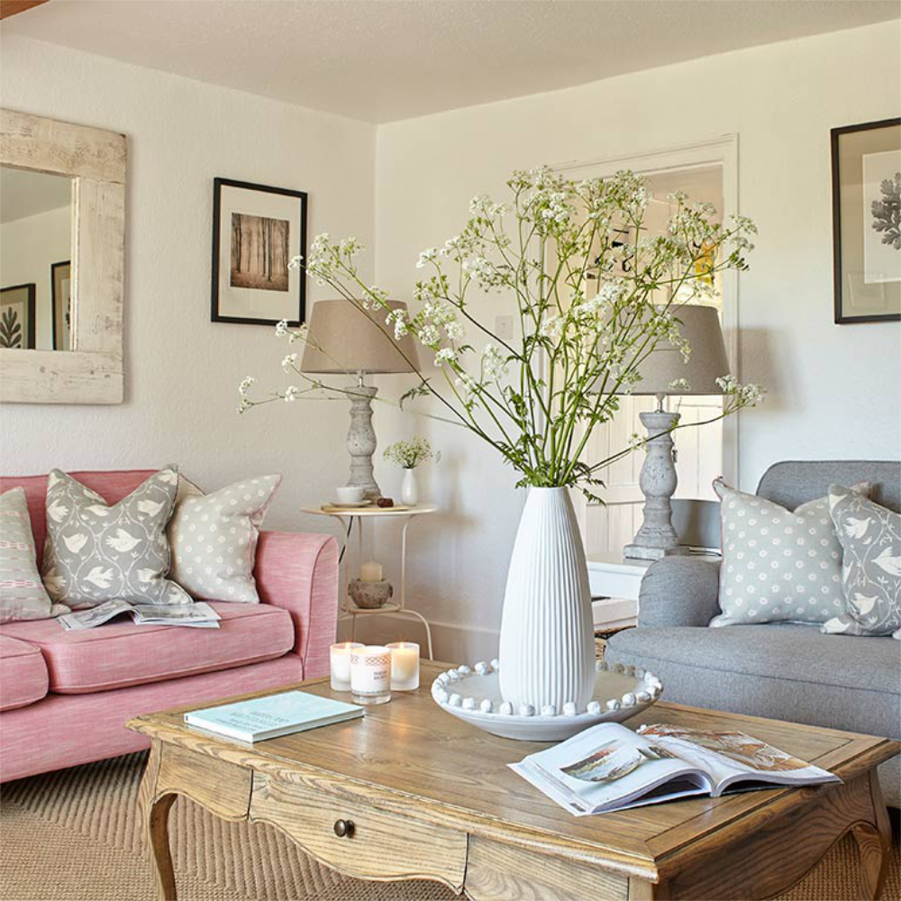 A pretty country livng room with a pink sofa.