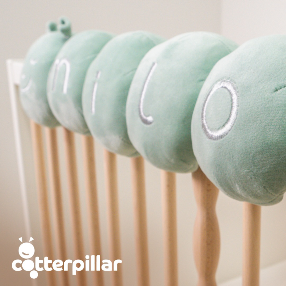 A soft velvet personalised caterpillar for a baby's cot