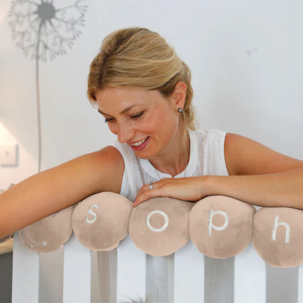A lady reaching down to a baby in a cot