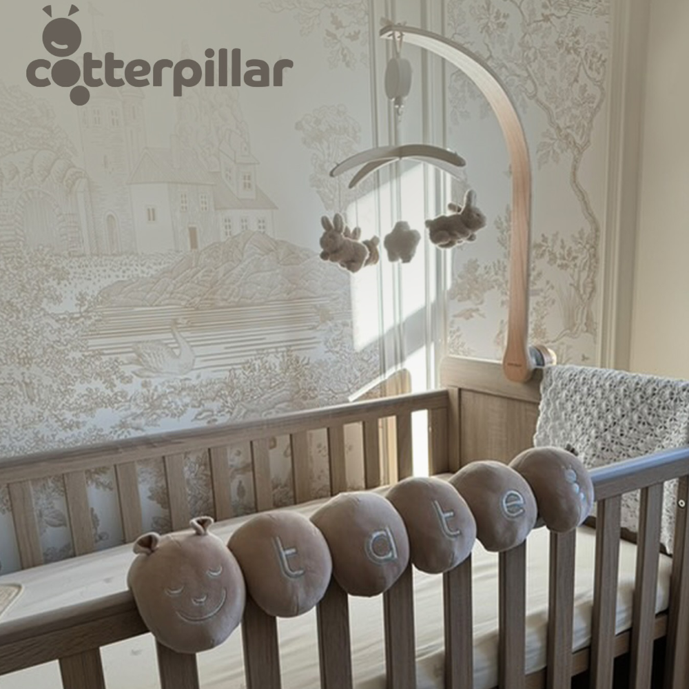 A baby's cot with hanging mobile and soft velvet personalised caterpillar