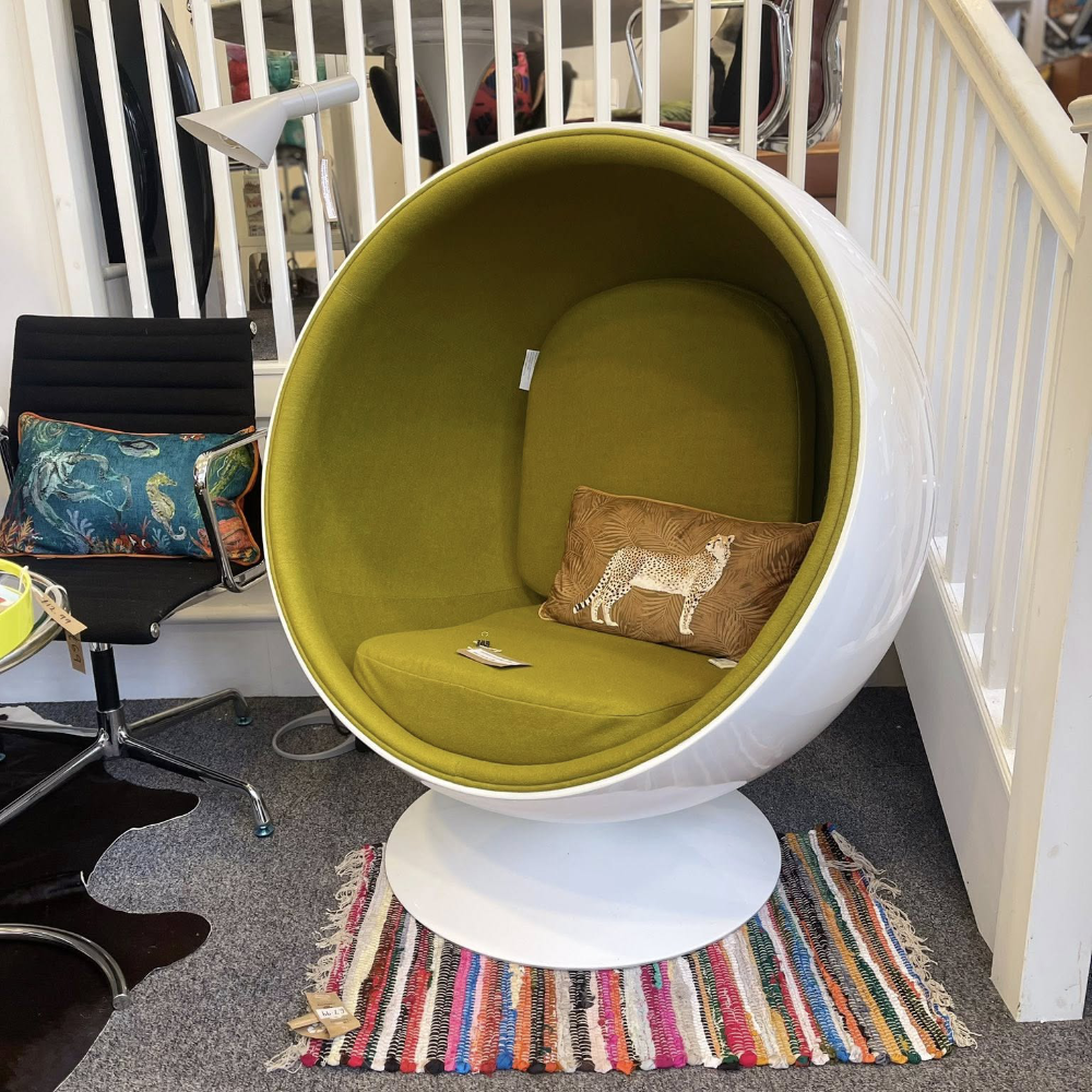A gloss white armchair pod with bright olive green interior and cushions