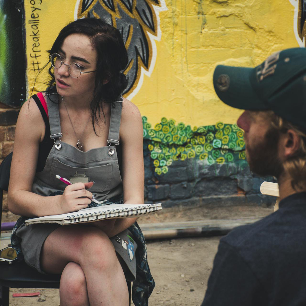A woman and a man sketching in the street.