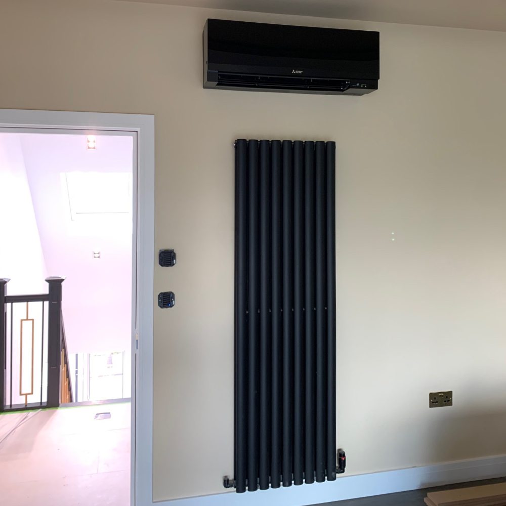 A black air conditioning unit above a modern black vertical radiator