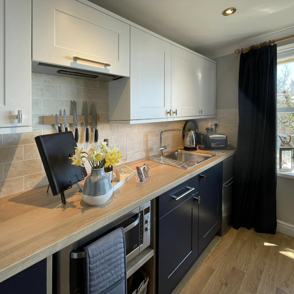 A shaker style kitchen in cream and navy with wooden worktops