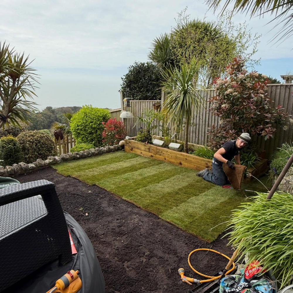 A man laying new turf in a garden