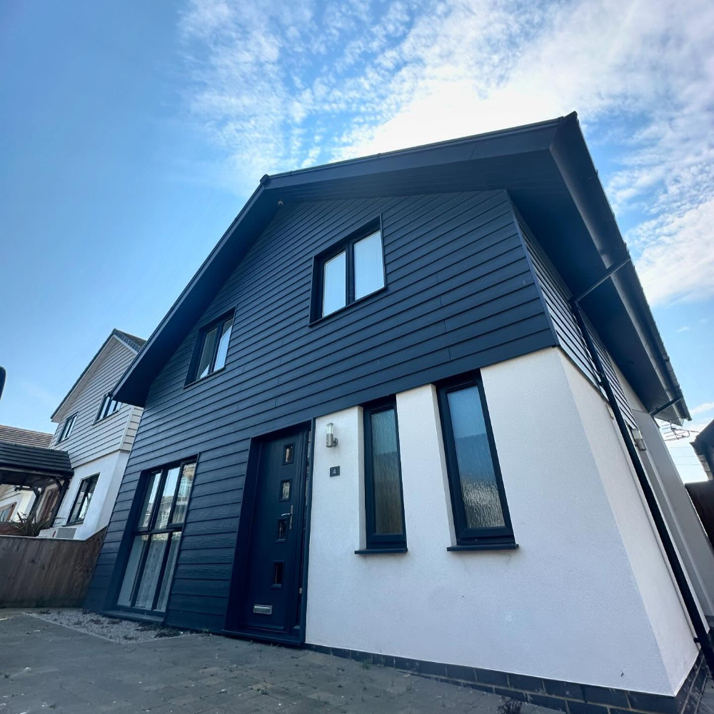 A modern house with an exterior finished in a mix of white render and black cladding.