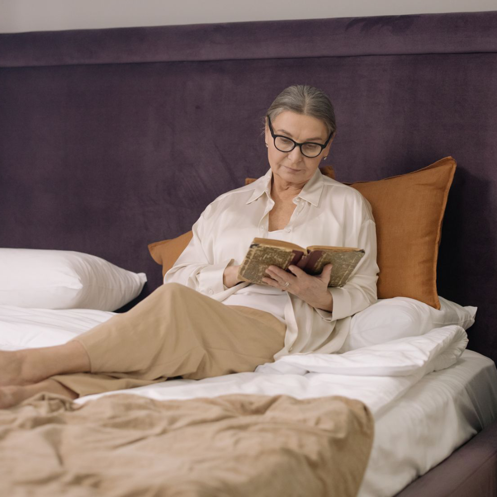 A lady reading a book in bed.