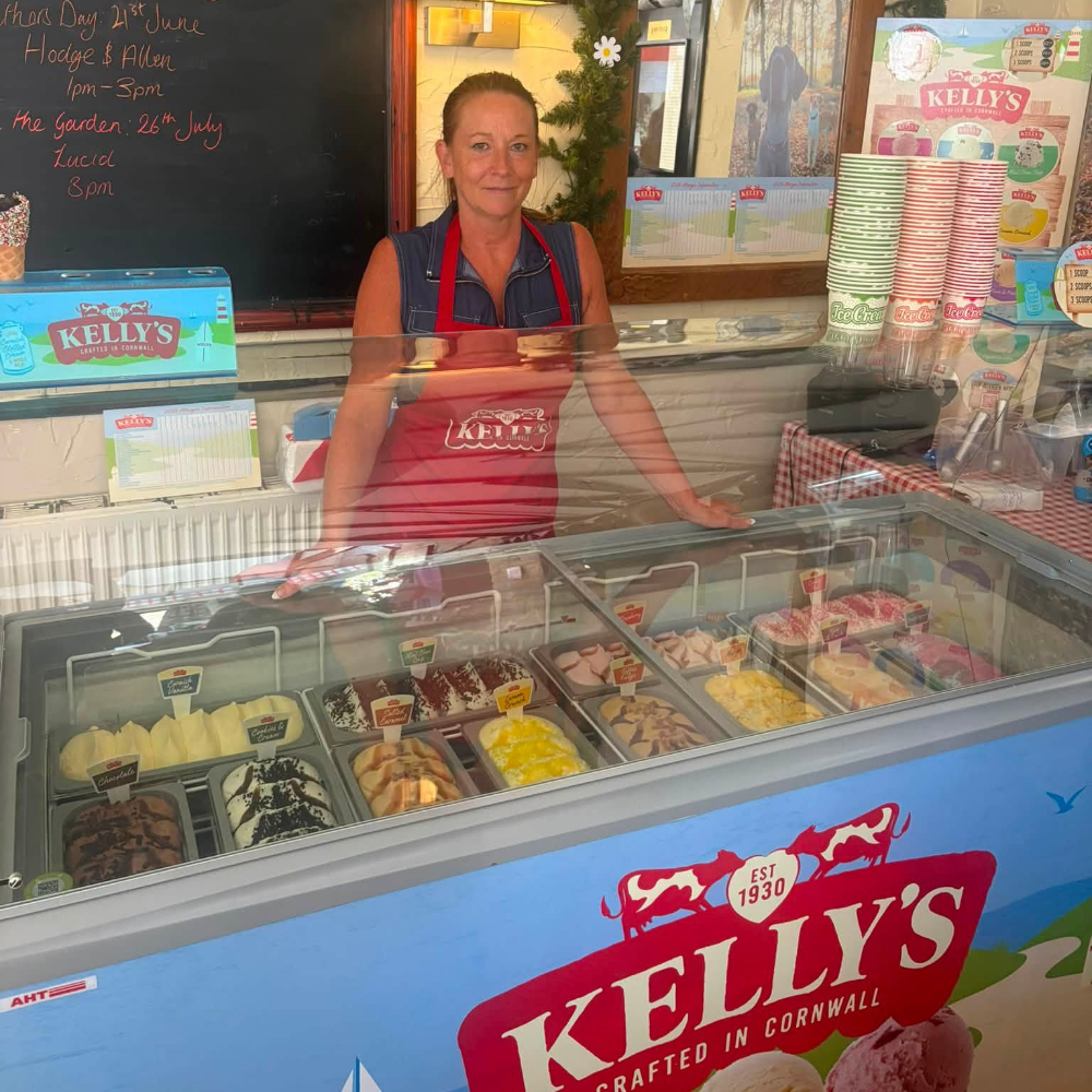 A lady serving at an ice cream counter.