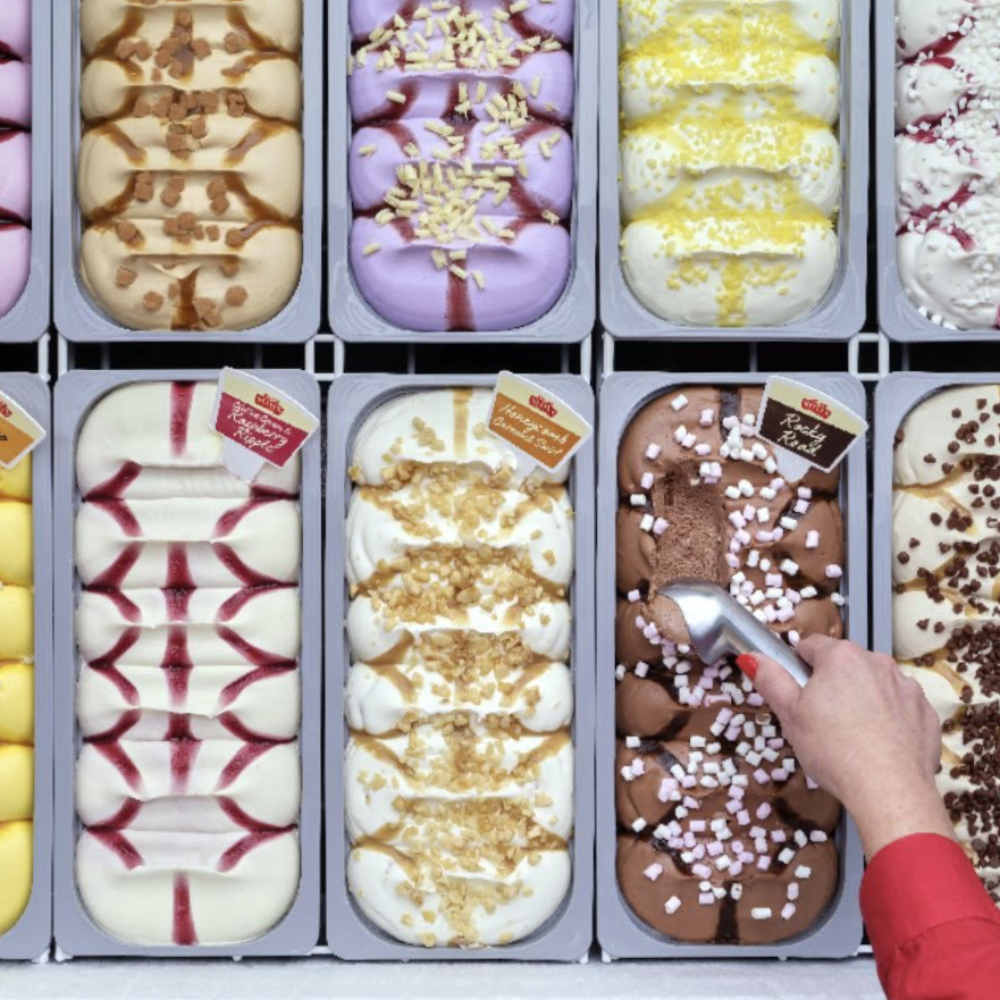 Someone scooping ice cream from a tub.