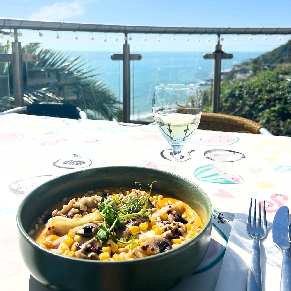 A dish of food on a table overlooking the sea.